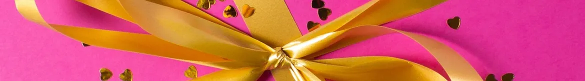 A golden ribbon tied on a bright pink background, adorned with small heart-shaped confetti for a festive touch.
