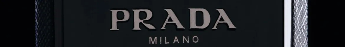 The Prada Milano logo in sleek silver lettering on a dark textured background, exuding luxury and sophistication.